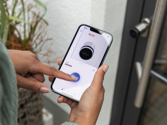 Frau öffnet die Haustür mit der ABUS One App am CYLOX One